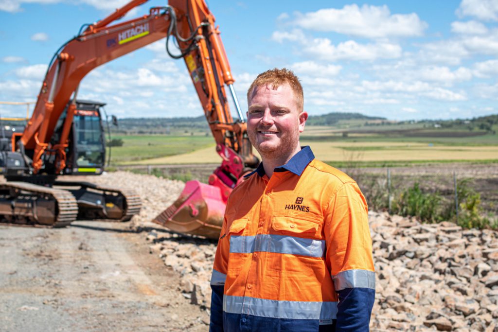 Haynes_Civil_worker standing in front of excavator 1